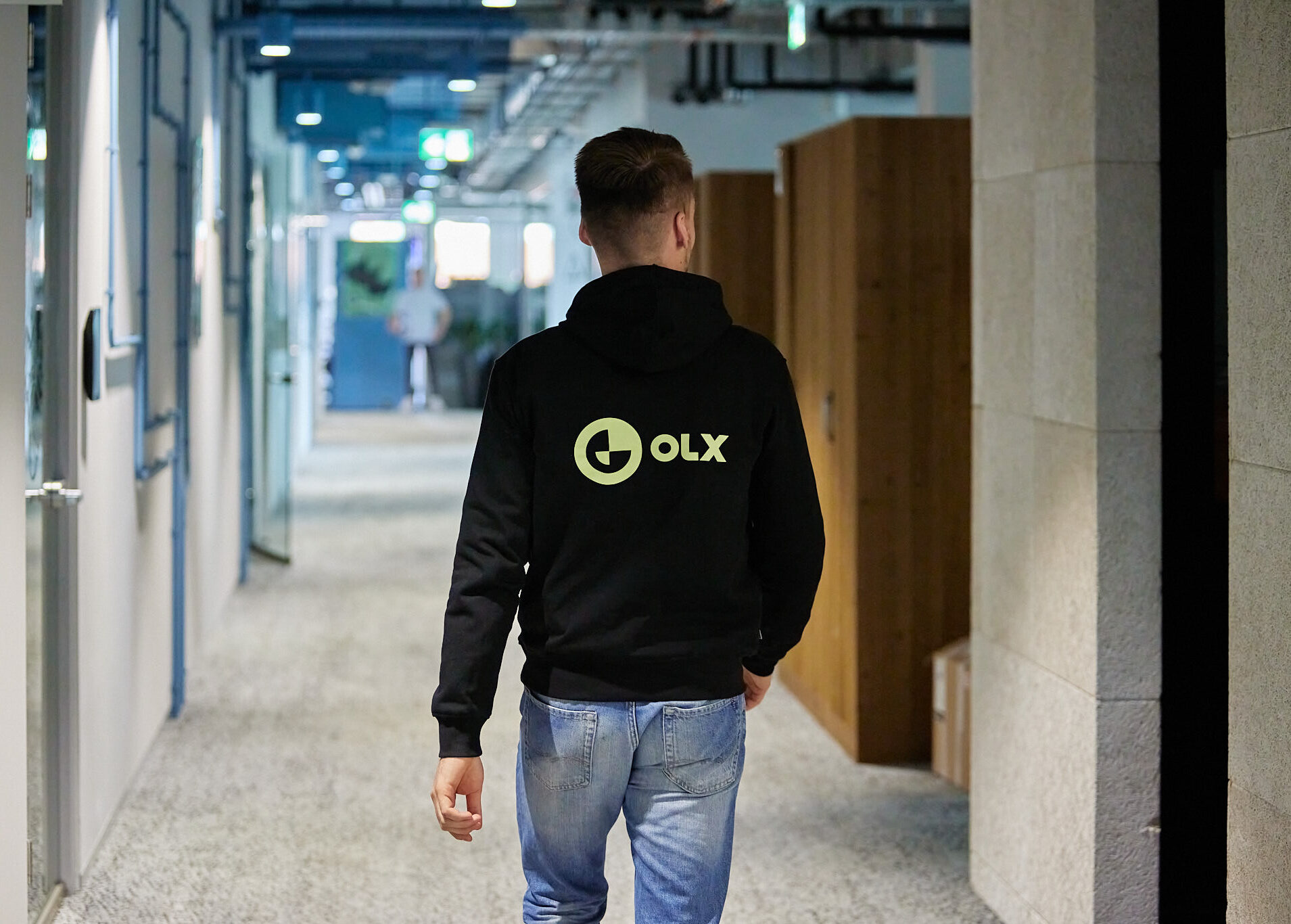 Man walking through the office with OLX hoodie